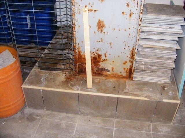 Bază de stâlp metalic cu rugină, pe un soclu de beton.